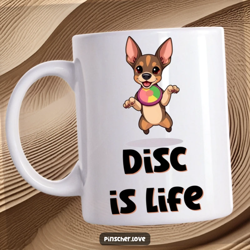 Funny Pinscher mug featuring a determined dog in mid-leap, eyes locked on a colorful flying disc, ready for action.