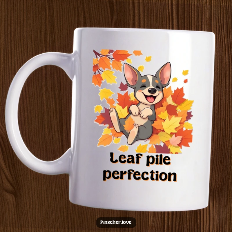 Funny Pinscher mug featuring an excited Pinscher dog gleefully rolling in a vibrant pile of colorful autumn leaves.
