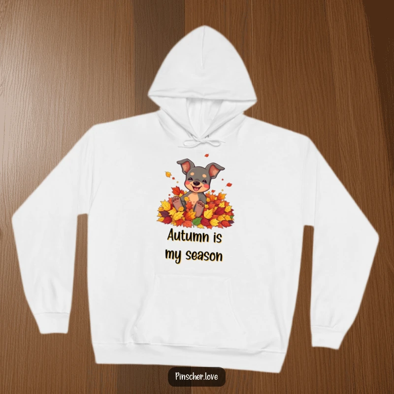 Funny, warm hoodie depicting a pinscher character joyfully rolling in a pile of colorful autumn leaves.
