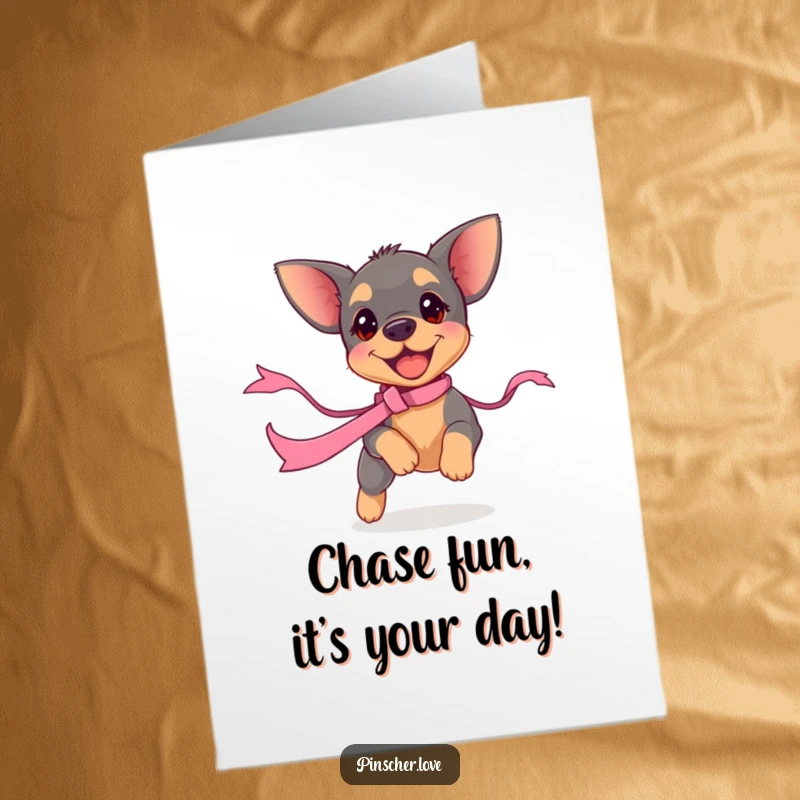 Funny Free Printable Birthday Card: Small pinscher puppy with boundless energy, joyfully chasing a bright red ribbon.