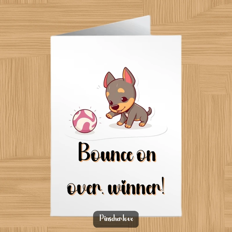 Funny Free Printable Congrats Card: A mischievous pinscher dog joyfully nudging a bouncing, crinkly ball, capturing playful celebration.