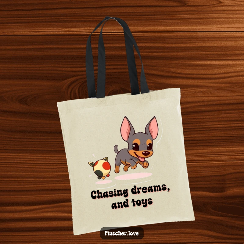Funny tote bag with an energetic pinscher character focused on chasing a small, fleeing toy.