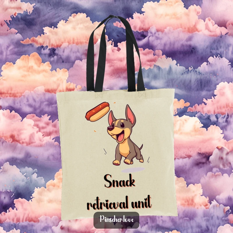 Funny Pinscher dog tote bag, hilariously yipping and pursuing a floating hotdog with determined enthusiasm and wagging tail.