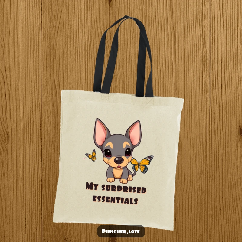 Funny Surprised Pinscher Tote Bag: A cute pinscher with floppy ears displays comical surprise upon encountering a butterfly, perfect for daily use.